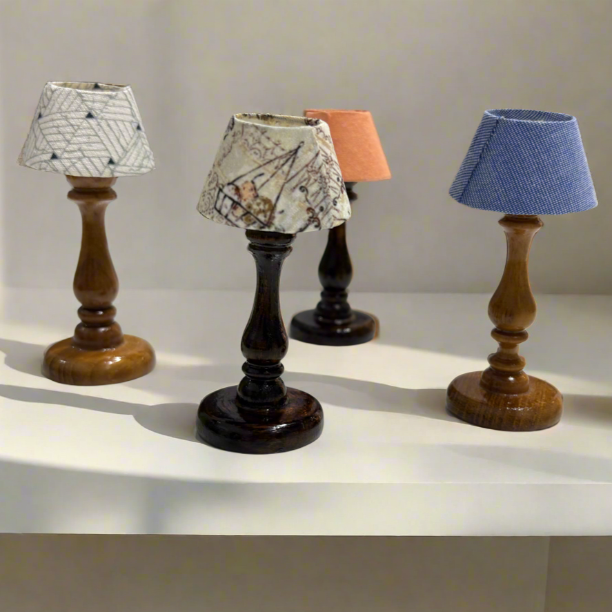 Set of small table lamps with various lampshades on a white surface.
