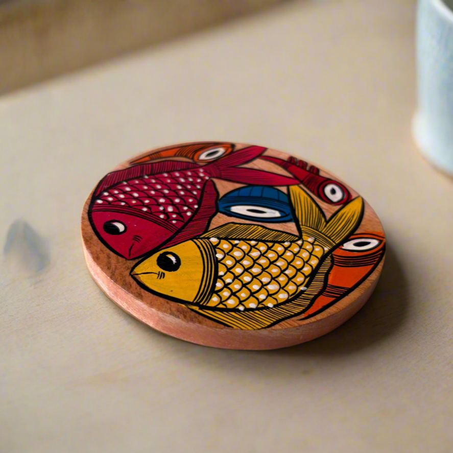 Wooden coaster with fish design on a table next to a mug
