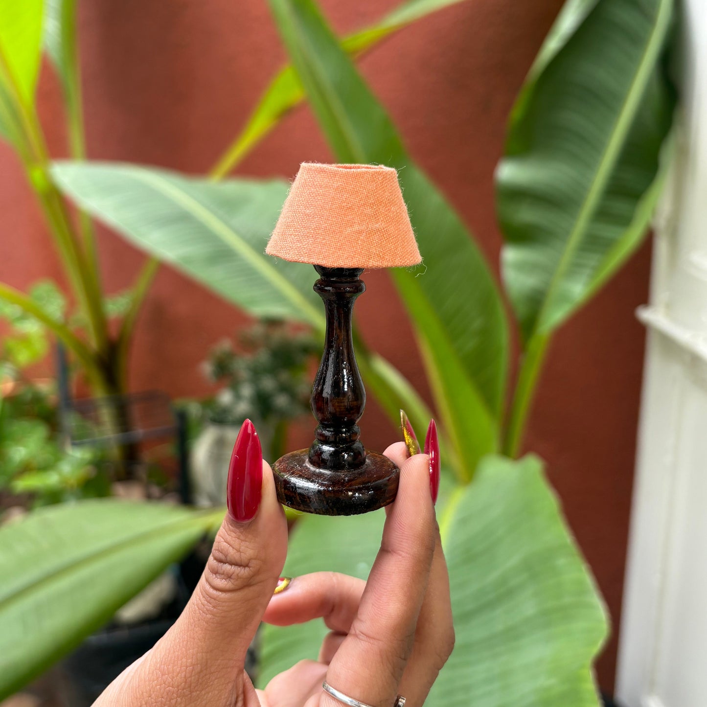 Person holding a small bottle with a sponge against a plant background