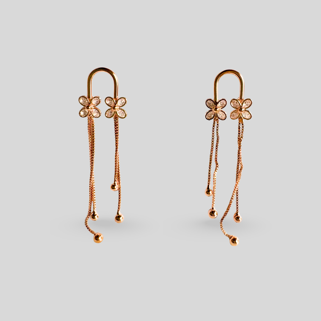 Rose gold earrings with floral designs on a light gray background