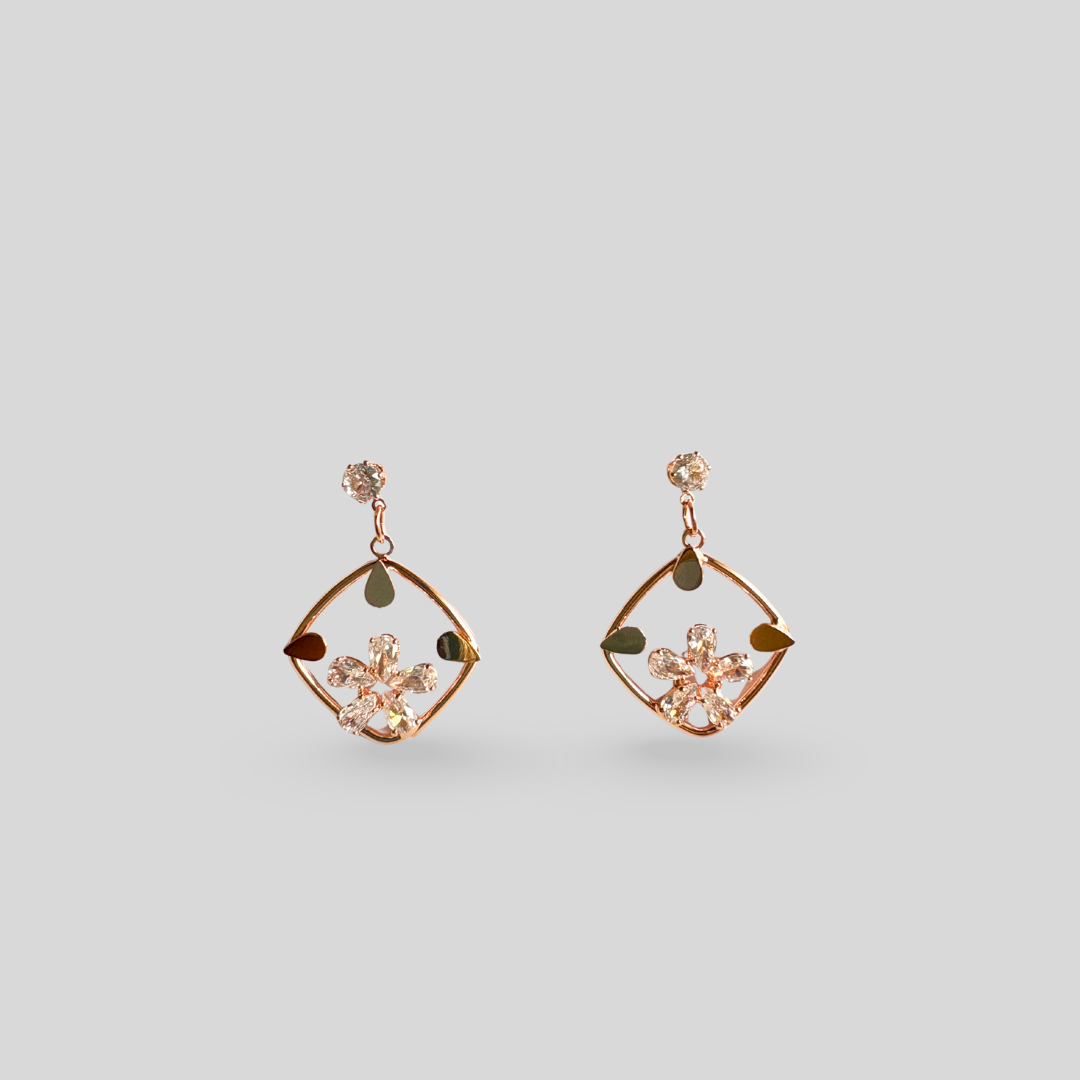 Rose gold earrings with floral design on a light gray background